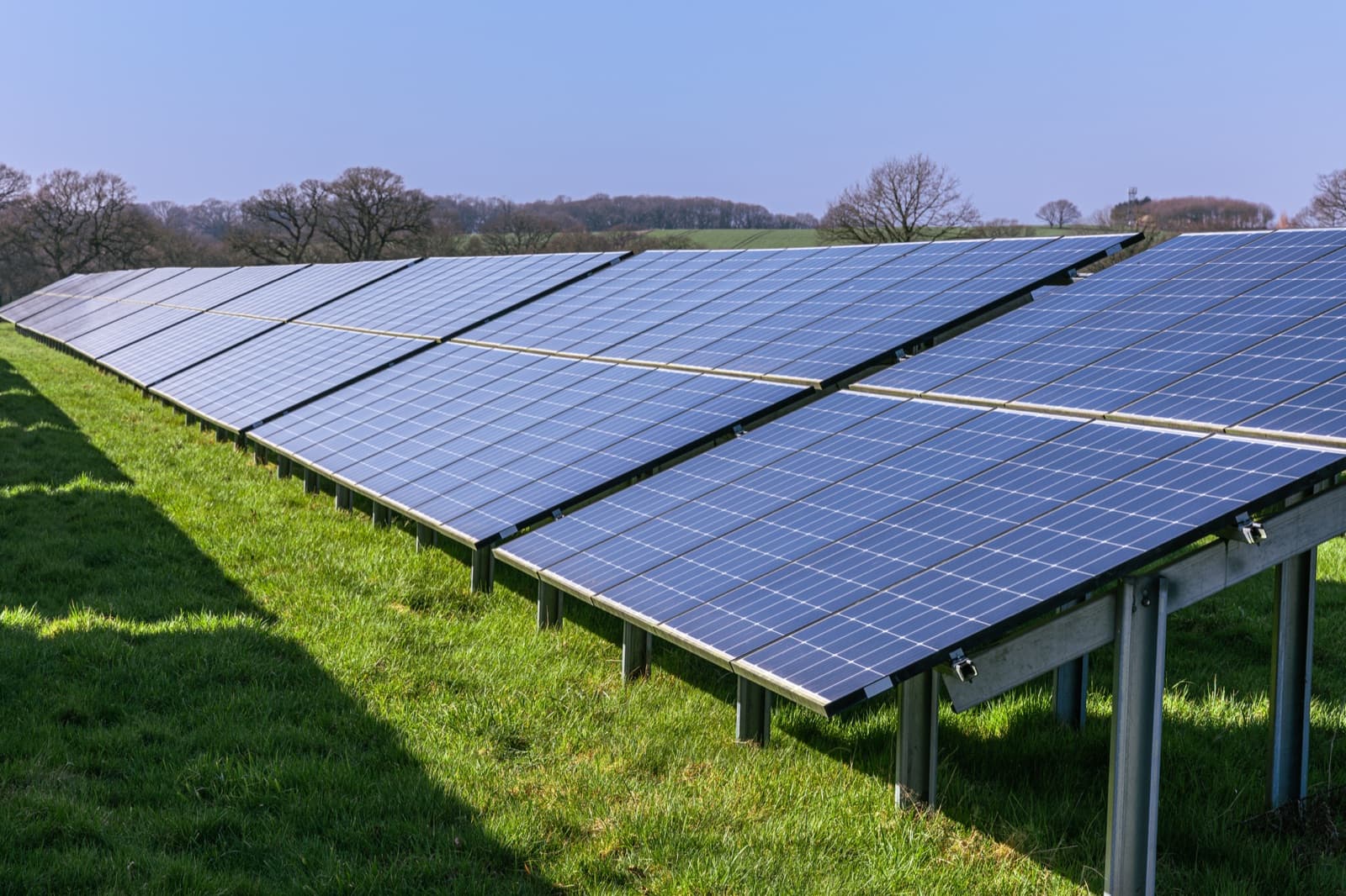 Fixed-tilt ground-mount solar array rows on grass