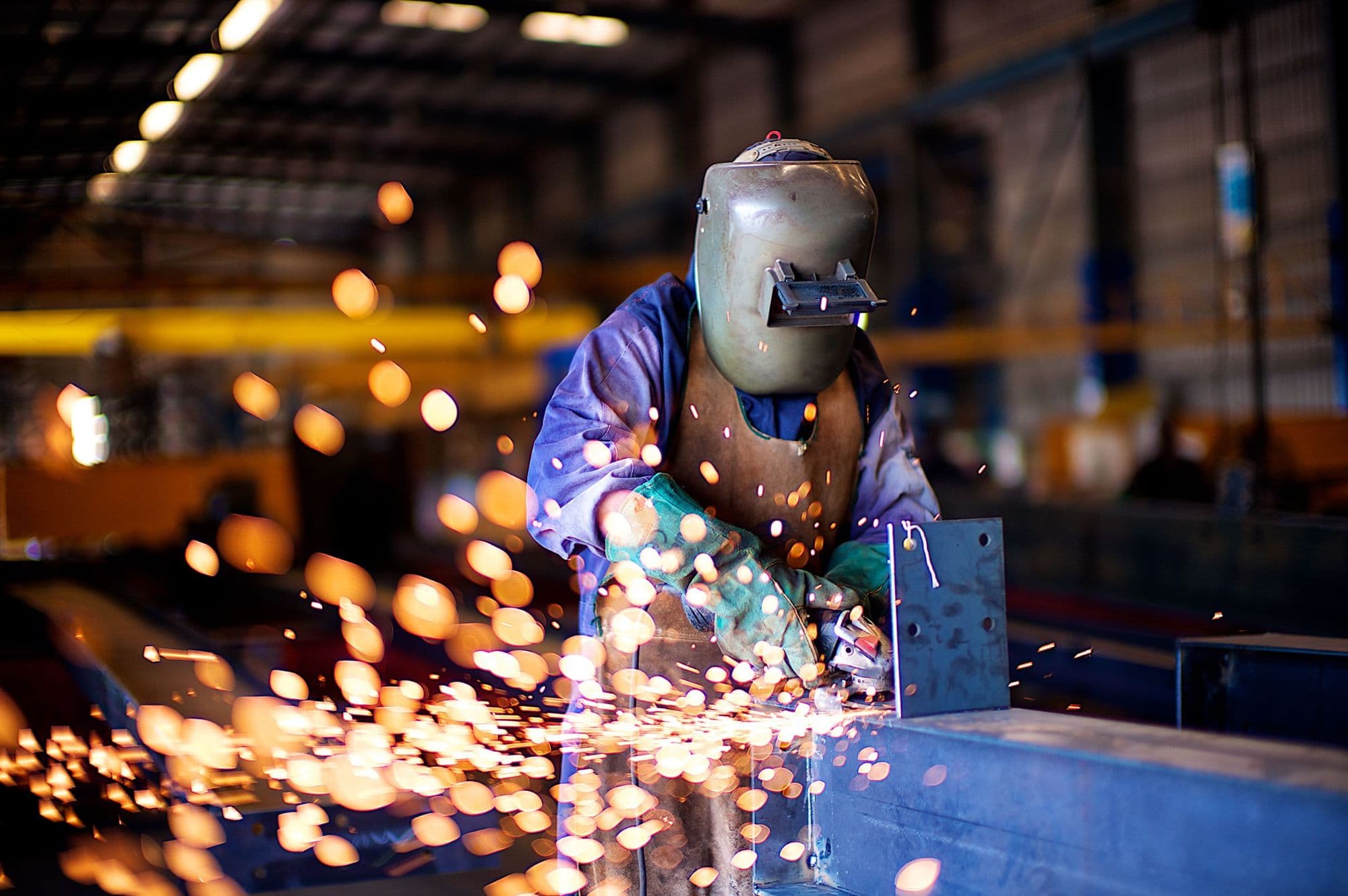 Welder working on a steel structure in a fabrication facility